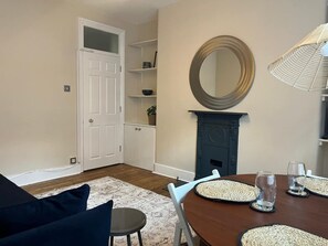 A dining area with a wooden table, chairs, and a mirror above it.