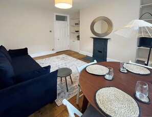 A dining area with a wooden table, woven placemats, and a round mirror above it.