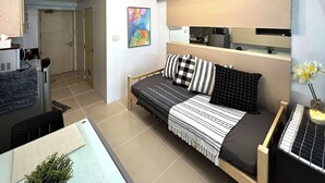 A compact studio apartment with a bed, kitchenette, and a small dining area. - Stylish 1-Bedroom at Sea Residences, Pasay — close to SM Mall of Asia! (Pasay City)