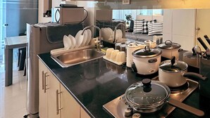 A modern kitchen with stainless steel appliances, a dish rack, and a variety of pots and pans. - Stylish 1-Bedroom at Sea Residences, Pasay — close to SM Mall of Asia! (Pasay City)