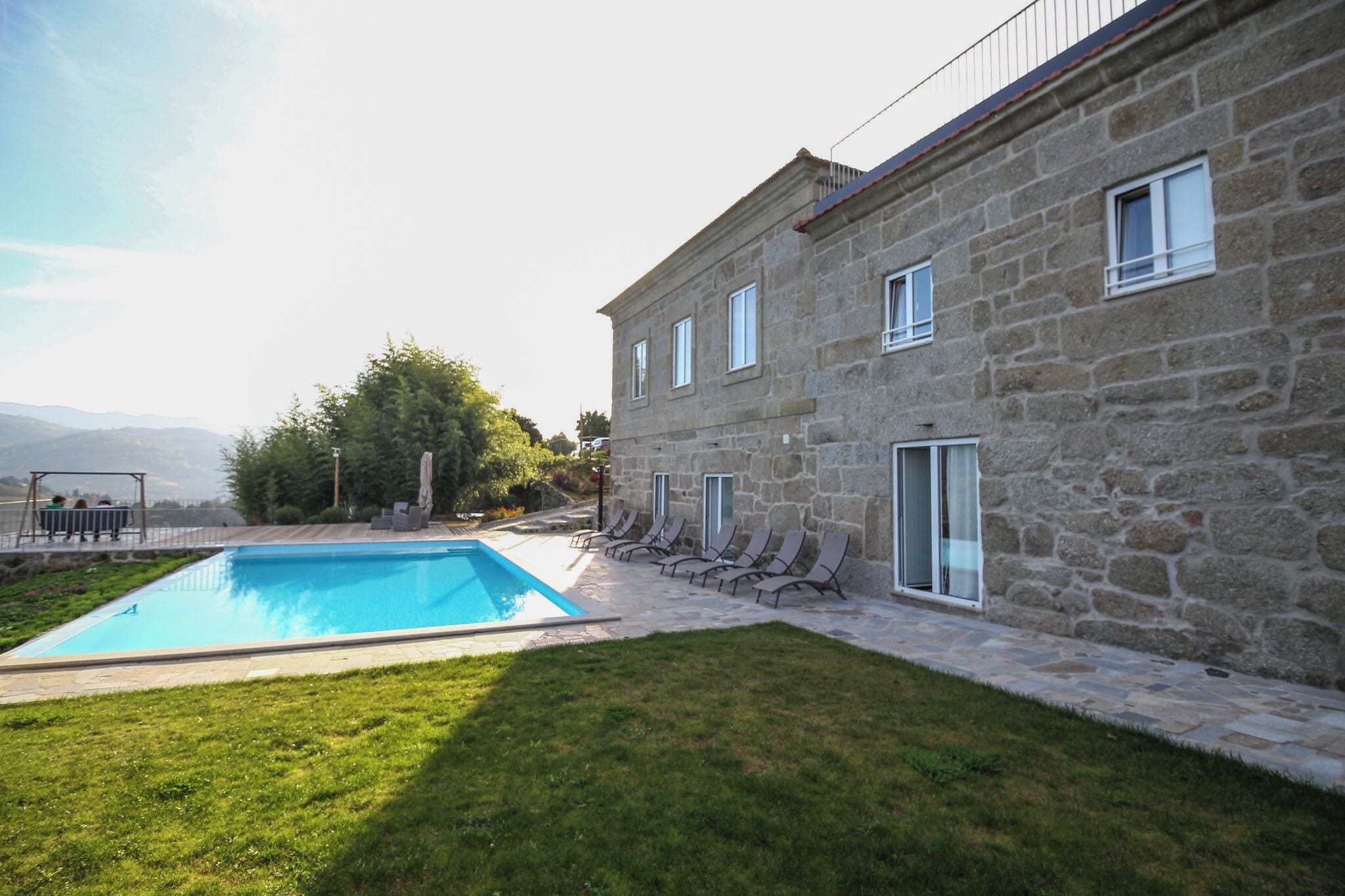 Un edificio de piedra con piscina y césped.