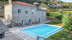 A stone building with a swimming pool, a wooden deck, and a view of the surrounding landscape. - Bosque da Fantasia (Baiao)