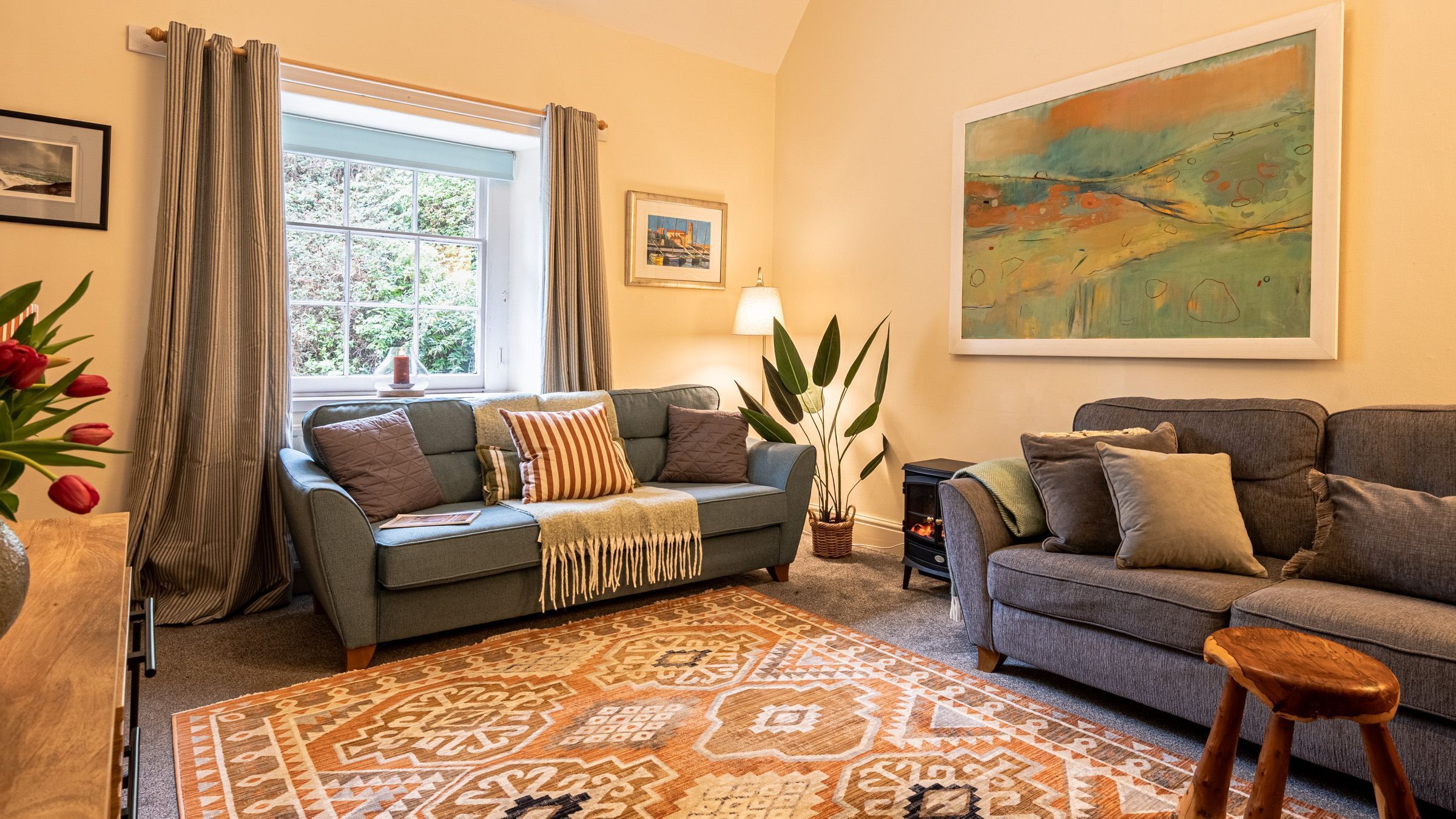 A cozy living room with two sofas, a patterned rug, and a large painting on the wall.