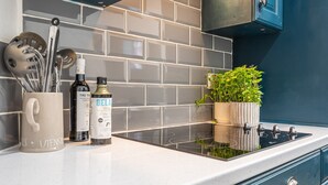 A kitchen with a white countertop, a stainless steel stove, a potted plant, and kitchen utensils. - Glyn y Weddw - sleeps 8 guests  in 4 bedrooms (Llanbedrog)