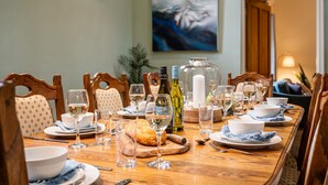 A dining table set for a meal with wine glasses, plates, and a bread basket. - Glyn y Weddw - sleeps 8 guests  in 4 bedrooms (Llanbedrog)