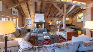 A cozy log cabin interior with a fireplace, wooden beams, and comfortable seating. - CHALET NEIGE - Six Bedroom Chalet, Sleeps 12 (Verbier)