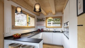 Eine moderne Küche mit Holzbalken, weißen Schränken und zwei Barhocker.