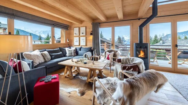Ein gemütlicher Holzraum mit Sofa, Tisch und Kamin.