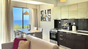 Uma sala de estar moderna com sofá, mesa de jantar e área de cozinha.