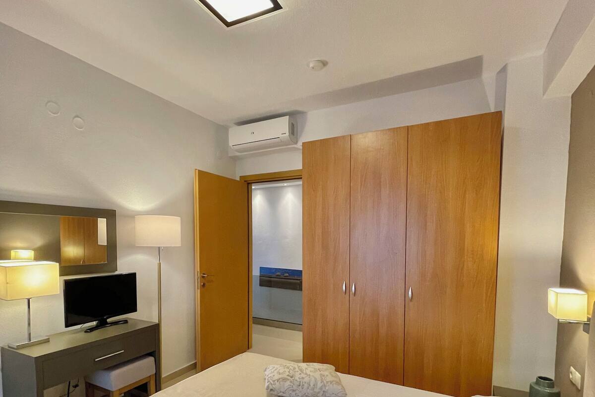 Une chambre d’hôtel comprenant un lit, un bureau avec une télévision, une armoire et un appareil de climatisation.