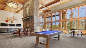 A pool table in a room with stone walls, large windows, and wooden ceiling beams. - Grand Timber Lodge Studio Ski in/out (Breckenridge)