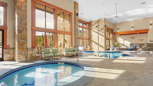 An indoor swimming pool area with multiple pools, stone walls, and wooden beams. - Grand Timber Lodge Studio Ski in/out (Breckenridge)