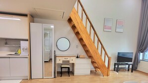 A modern living space with a wooden staircase, a dining area, and a kitchen. - JS House (Seoul)