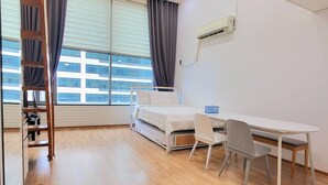 A room with a bed, a desk, a chair, and a window with curtains. - JS House (Seoul)