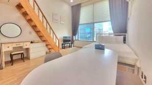 A modern hotel room with a wooden staircase, a desk, a large bed, and a view of the city through the window. - JS House (Seoul)