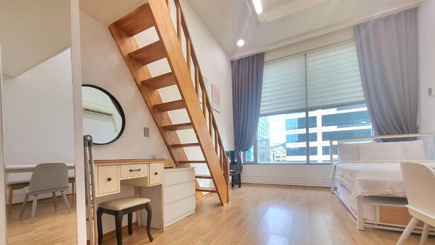 A modern bedroom with a wooden ladder, a desk, a chair, a bed, and a large window with curtains. - JS House (Seoul)