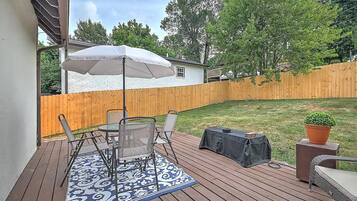A deck with a table and chairs, a covered umbrella, and a potted plant.