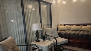 Um quarto acolhedor com um sofá, duas poltronas, uma mesinha com abajur e uma garrafa de champanhe.