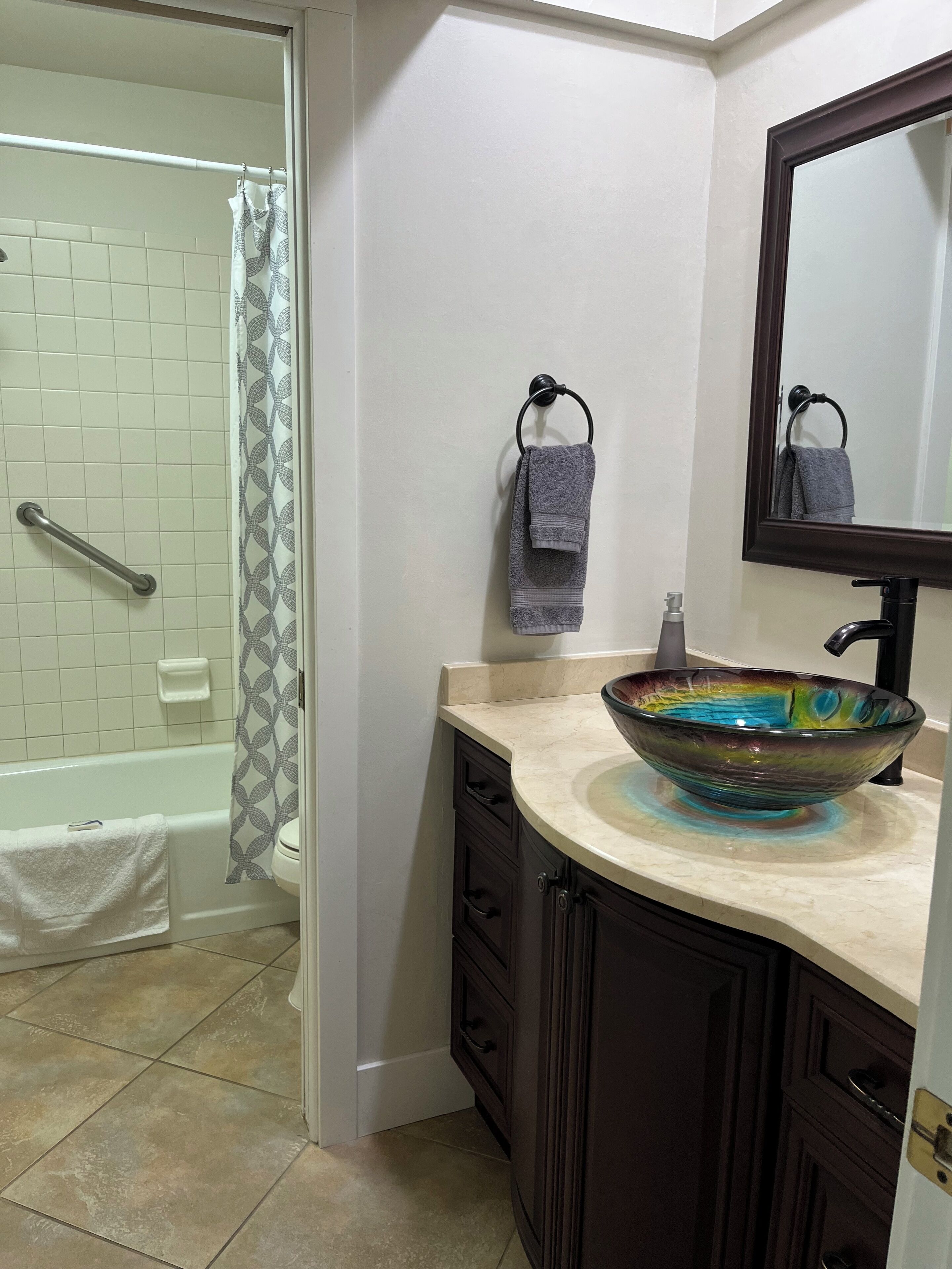 A bathroom with a bathtub, a sink with a decorative bowl, a towel rack, and a mirror.