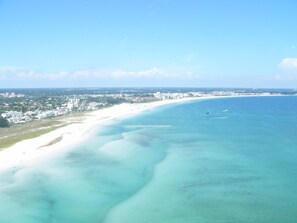 Un paysage urbain côtier avec une vaste plage de sable et une mer bleue et limpide.