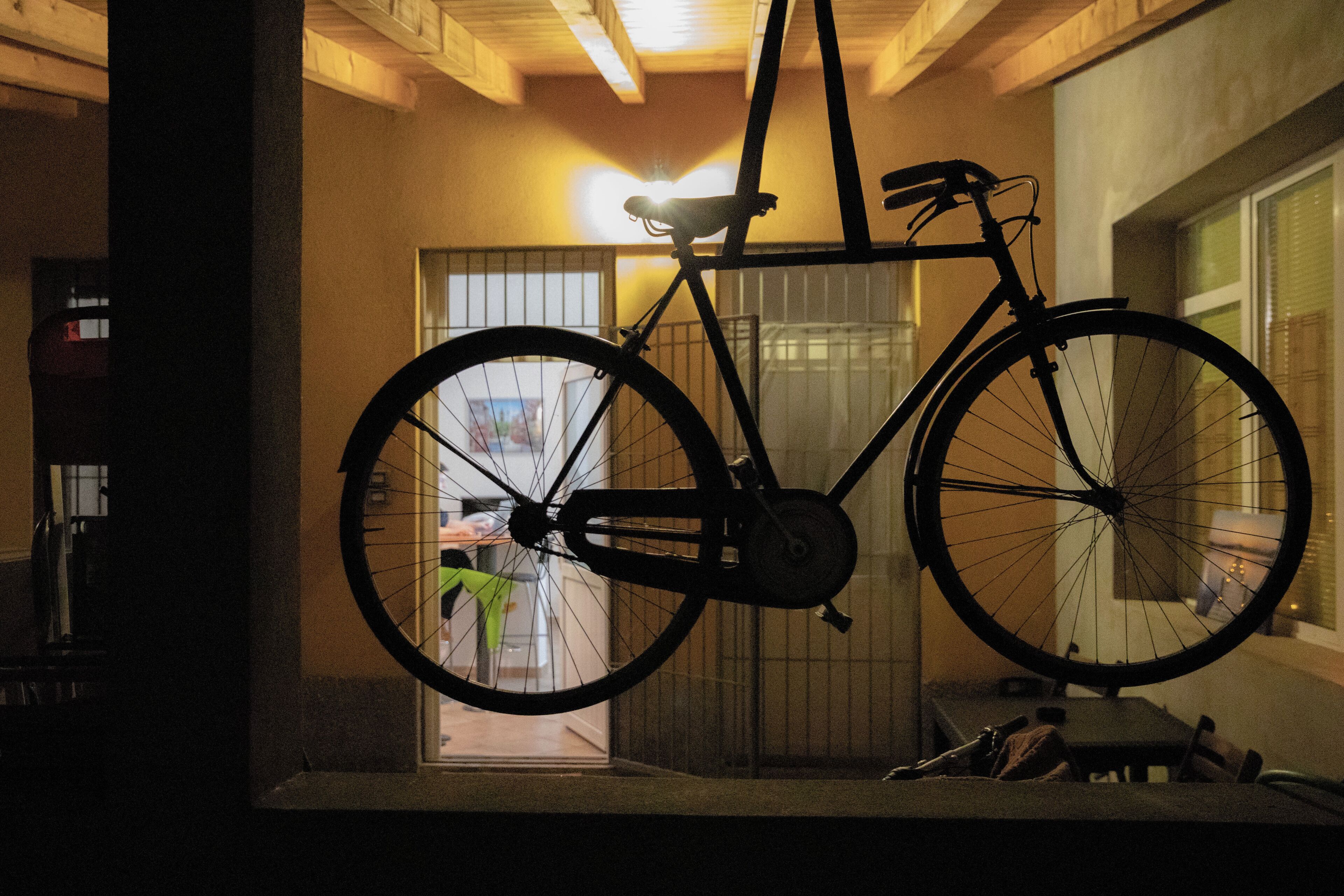 A bicycle hanging in a doorway with a view of a room in the background.