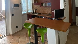 A modern kitchen with a wooden countertop, two green bar stools, and a built-in oven. - Da Colomba city center (Bergamo)