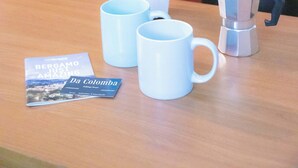 A kitchen with a wooden table, a coffee pot, two white mugs, and a brochure titled "Bergamo Just Amazing Da Colomba". - Da Colomba city center (Bergamo)