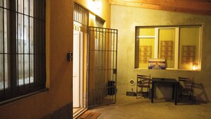 A room with a wooden ceiling, a window with blinds, a door with a metal gate, and a small table with chairs. - Da Colomba city center (Bergamo)