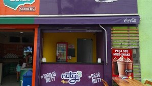A food stall with signs for 'Frutos de Goiás' and 'Nutty Açaí'.