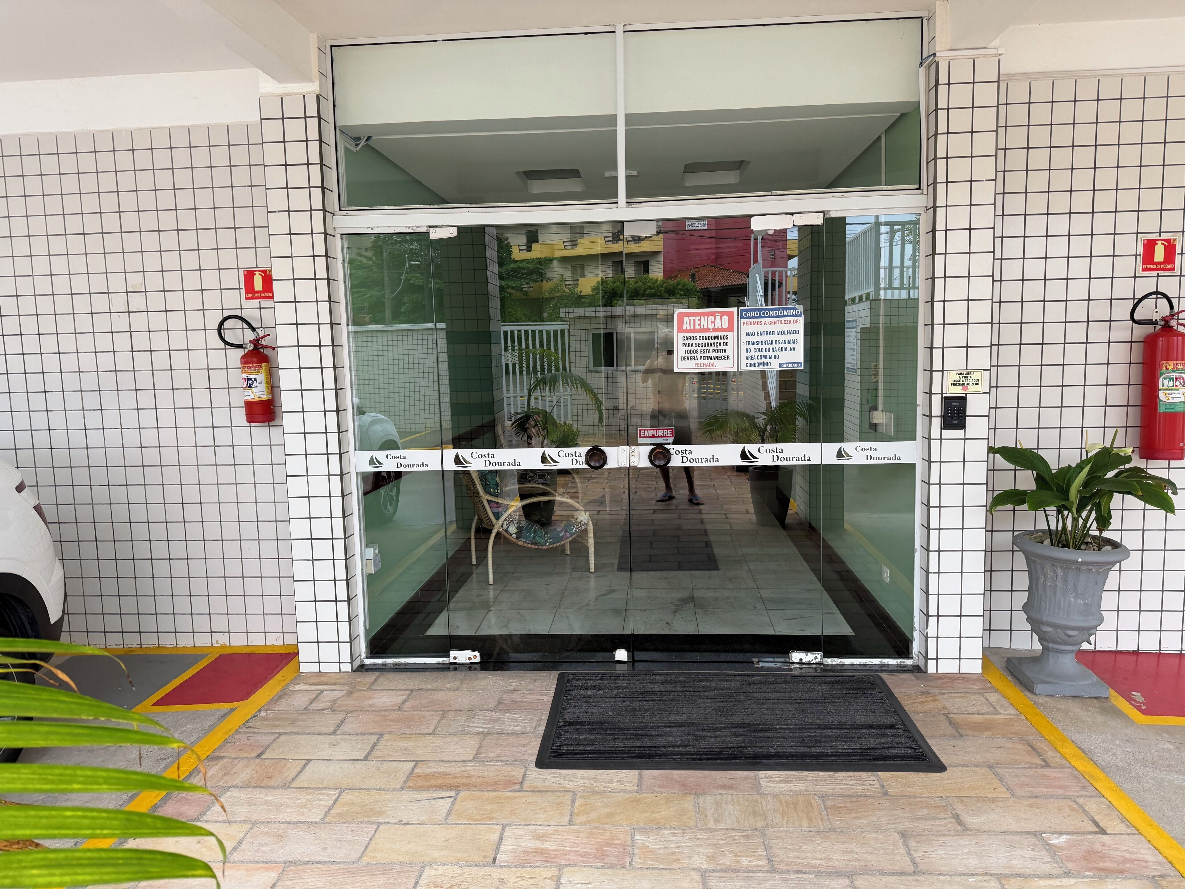 A hotel entrance with a glass door, fire extinguisher, and a sign indicating a car parking area.
