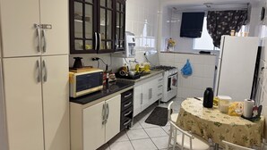 A kitchen with white cabinets, a microwave, a gas stove, and a table with chairs.