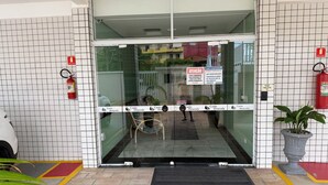 A hotel entrance with glass doors, a fire extinguisher, a sign, and a potted plant.