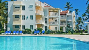 Un hotel con piscina, varios balcones y palmeras.