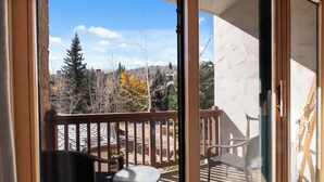 A balcony with a glass door, a small table, and two chairs. - Oxford Court 206 - 2 Bedroom Residence (Beaver Creek)