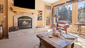 A cozy living room with a fireplace, a flat-screen TV, and a comfortable leather chair. - Oxford Court 206 - 2 Bedroom Residence (Beaver Creek)