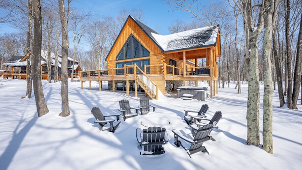 Une cabane en rondins dotée d’une terrasse et d’un espace salon extérieur.