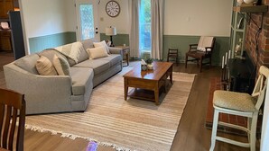 Un salon chaleureux avec un canapé gris, une table basse en bois et une cheminée.