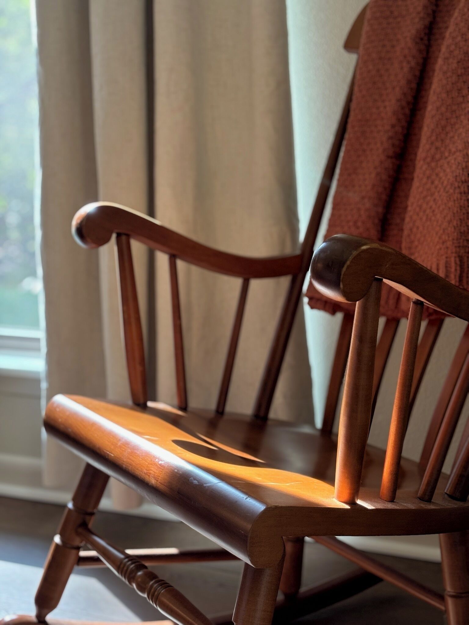 A wooden rocking chair with a curved backrest and a cushioned seat.
