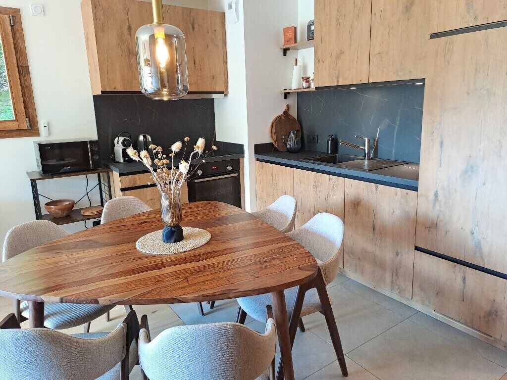 A modern kitchen with wooden cabinets, a black countertop, and a dining table with chairs.