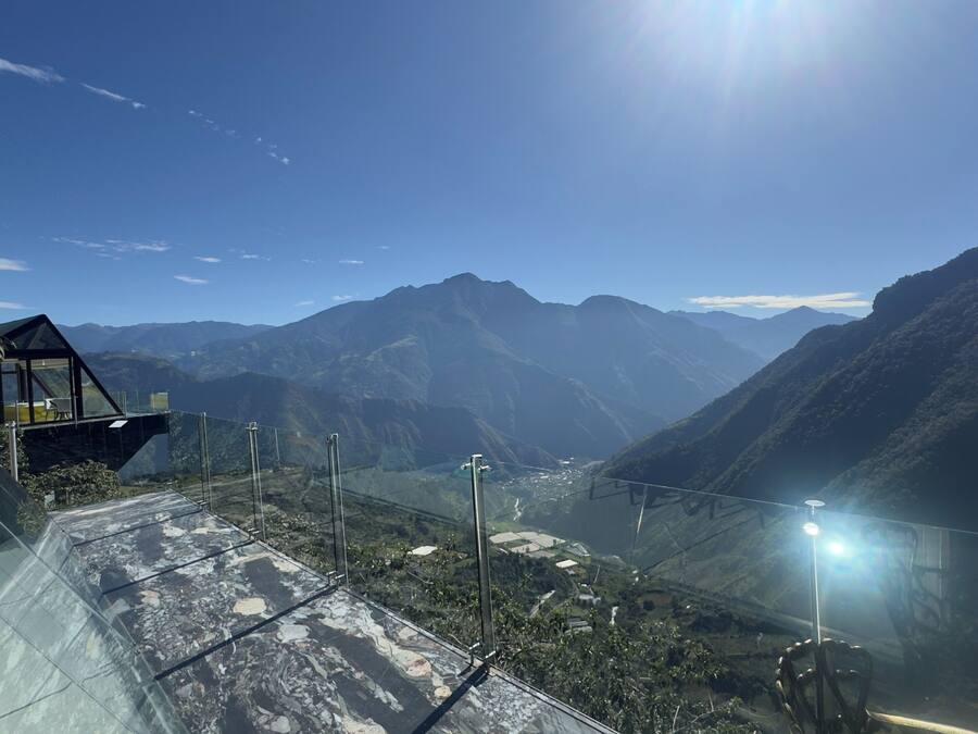 A glass-walled observation deck with a clear view of a mountainous landscape.
