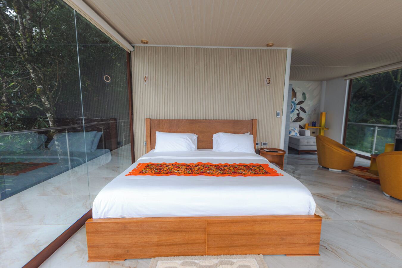 A modern bedroom with a large bed, a wooden headboard, and a glass balcony.