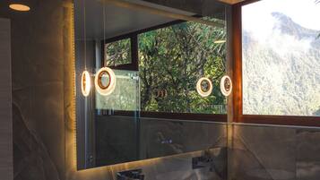 Un baño moderno con dos lavabos, un espejo grande y vistas a un paisaje montañoso.