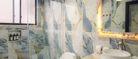 A modern bathroom with a glass-enclosed shower, a marble backsplash, and a vanity with a sink.