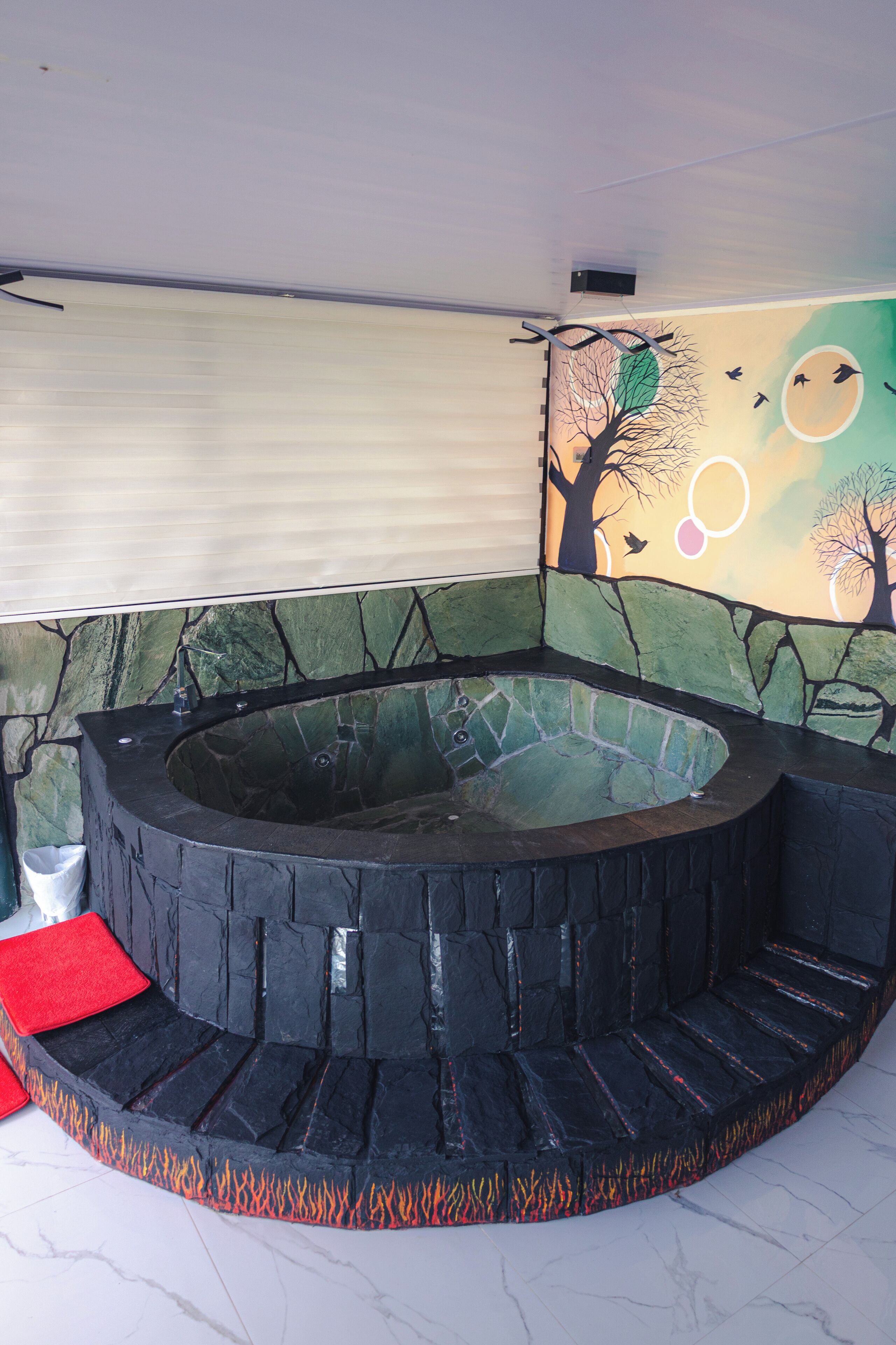 A circular hot tub with stone walls and a mural of trees and birds.