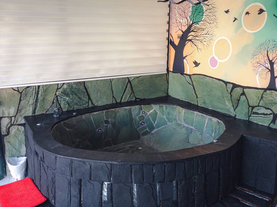 A circular hot tub with stone walls and a mural of trees and birds.