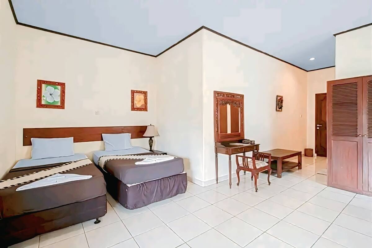 Une chambre avec deux lits, un bureau, une chaise et une armoire.