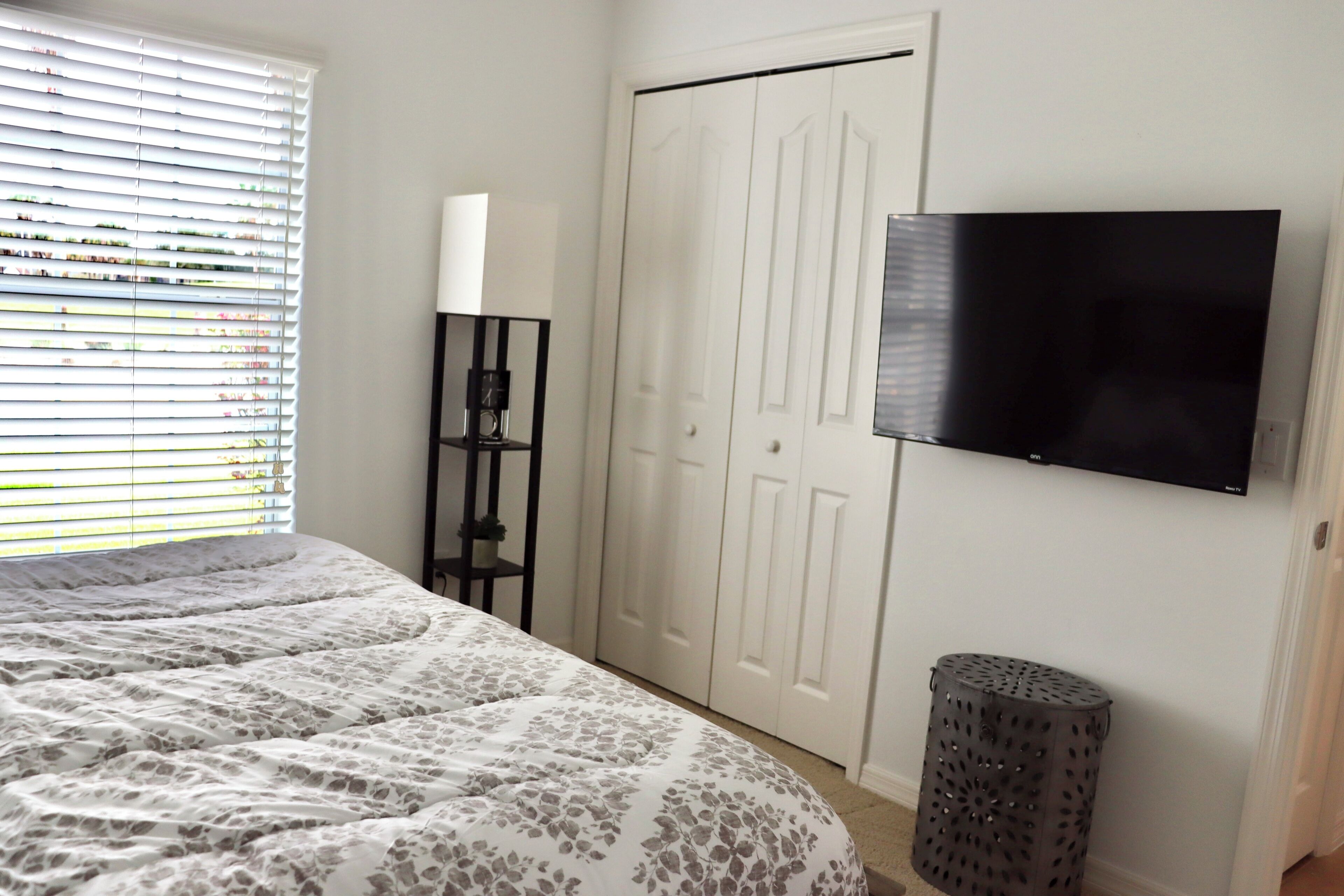 A bedroom with a bed, a wardrobe, a TV, and a trash bin.