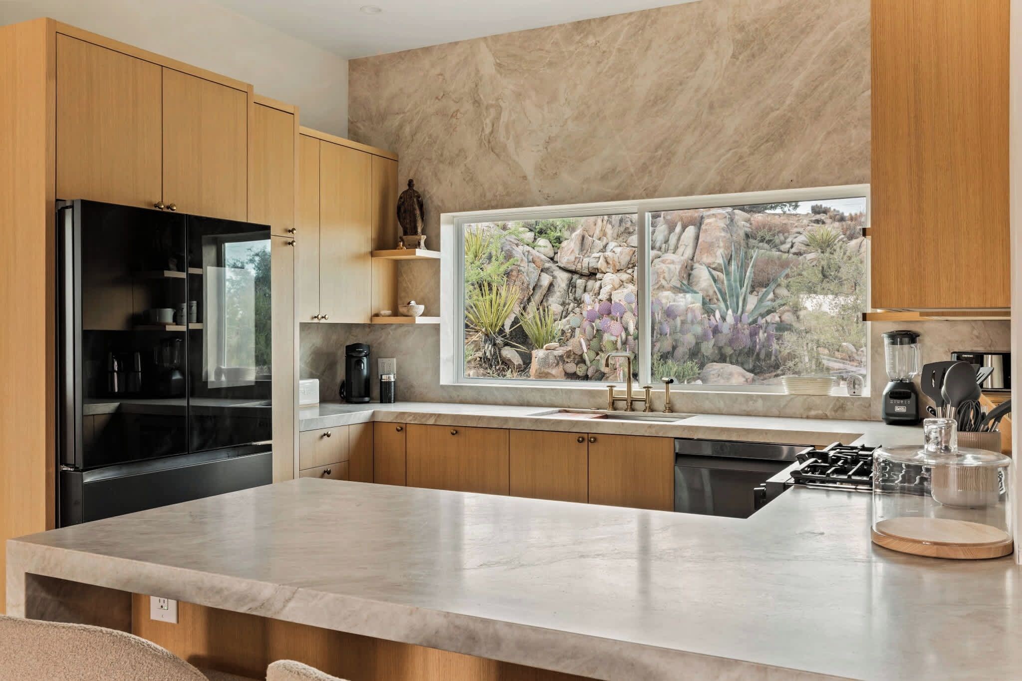 A modern kitchen with a large island, built-in appliances, and a view of a rocky landscape.