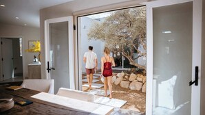 Un interior moderno con una mesa de madera, una puerta de cristal que da al exterior y un camino de piedra.