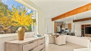 Una cocina moderna con vigas de madera, un comedor y un amplio ventanal con vistas a árboles.